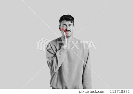 Man rubbing cheek in pain on gray background Man rubbing cheek in pain on gray background 113718821