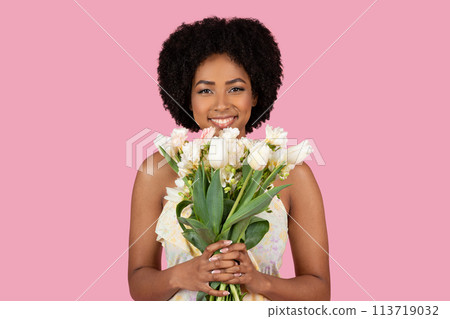 Smiling African American woman holding white flowers Smiling African American woman holding white flowers 113719032