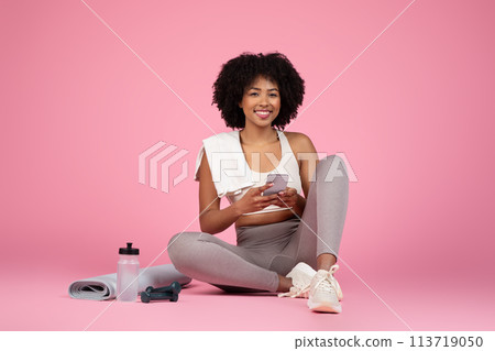 Relaxed lady sitting with smartphone on pink background 113719050