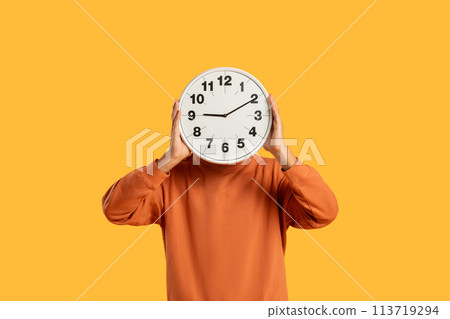 Man holding clock in front of face 113719294
