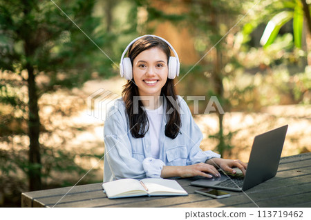 Smiling woman working with laptop in nature Smiling woman working with laptop in nature 113719462