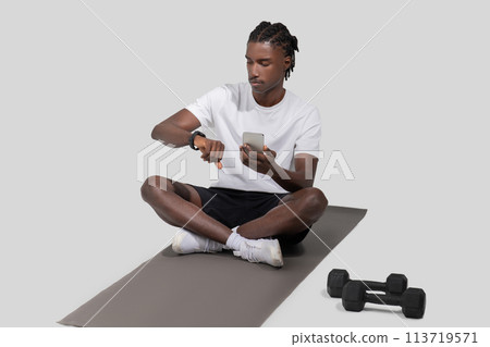 Man checking smartwatch while on a yoga mat 113719571