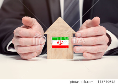 Businessman hand holding wooden home model with Iranian flag. insurance and property concepts 113719658