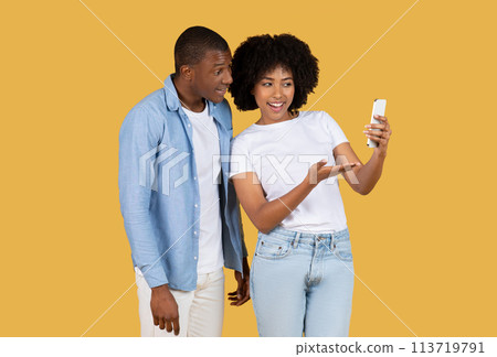 African American woman smiling and showcasing something on her smartphone screen 113719791