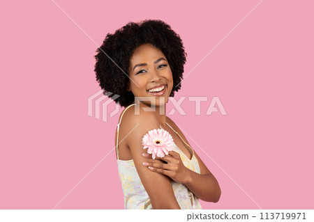 Smiling African American woman holding a pink flower 113719971