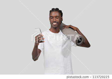 Smiling man holding phone and yoga mat Smiling man holding phone and yoga mat 113720225
