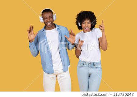 Couple with headphones and dancing gestures on yellow Couple with headphones and dancing gestures on yellow 113720247