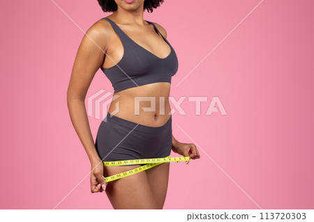 Woman measuring waist with a bright yellow tape measure Woman measuring waist with a bright yellow tape measure 113720303