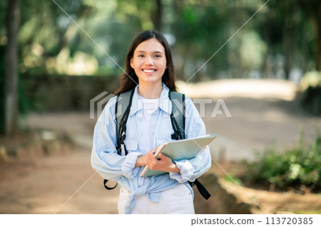 Content young female student with a radiant smile, dressed in white 113720385