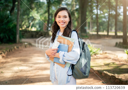 Beaming university student holding educational materials and a smart device 113720639