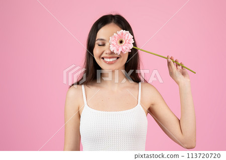 Joyful woman with a pink gerbera flower 113720720