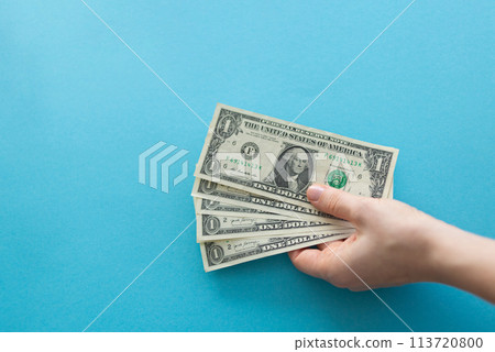 Hands holding dollars on a blue background with space for text 113720800