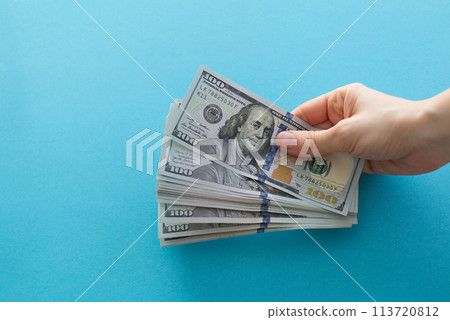 Hands holding dollars on a blue background with space for text 113720812
