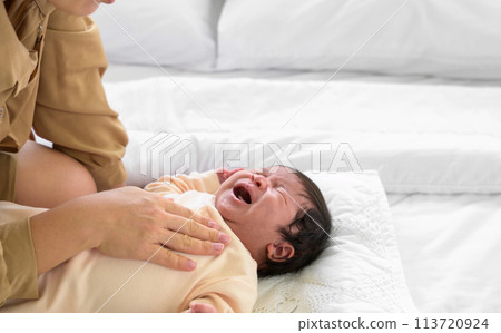 Unrecognizable mother caressing crying newborn baby girl on white bed at home Unrecognizable mother caressing crying newborn baby girl on white bed at home 113720924
