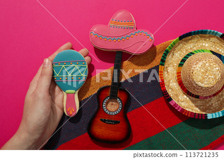 Mexican sombrero with a decorative guitar on a pink background 113721235