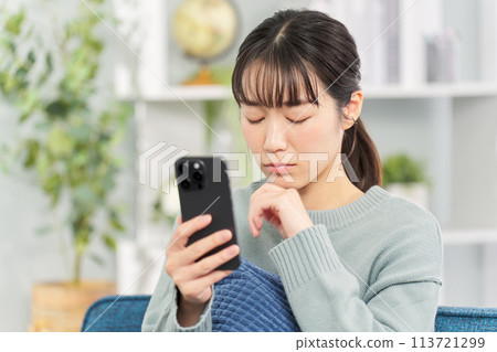 Sad woman looking at smartphone Sad woman looking at smartphone 113721299