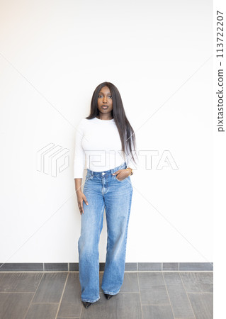 Modern Casual Style: Young Woman in White Top and Denim Jeans 113722207