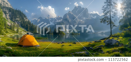 Beautiful campsite. Warm sunlight shine through the mountains onto green field. The lake and tranquil valley are visible in the background. We will experience an adventure amidst the beauty of nature. 113722562