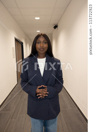 Confident Professional in Pinstripe Blazer Standing in Office Hallway Confident Professional in Pinstripe Blazer Standing in Office Hallway 113722923