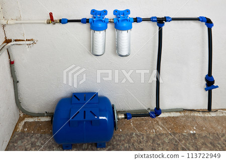 String wound cartridge filters and water storage pressure tank are connected to domestic water supply in utility room of residential. String wound cartridge filters and water storage pressure tank are connected to domestic water supply in utility room of residential. 113722949