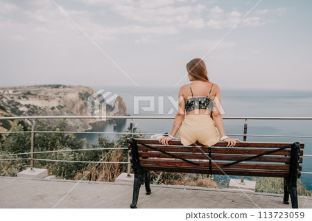Woman travel sea. Happy tourist enjoy taking picture outdoors for memories. Woman traveler looks at the edge of the cliff on the sea bay of mountains, sharing travel adventure journey Woman travel sea. Happy tourist enjoy taking picture outdoors for memories. Woman traveler looks at the edge of the cliff on the sea bay of mountains, sharing travel adventure journey 113723059