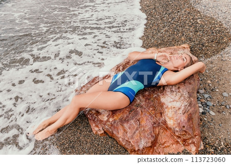 Woman summer travel sea. Happy tourist in blue bikini enjoy taking picture outdoors for memories. Woman traveler posing on the beach surrounded by volcanic mountains, sharing travel adventure journey Woman summer travel sea. Happy tourist in blue bikini enjoy taking picture outdoors for memories. Woman traveler posing on the beach surrounded by volcanic mountains, sharing travel adventure journey 113723060