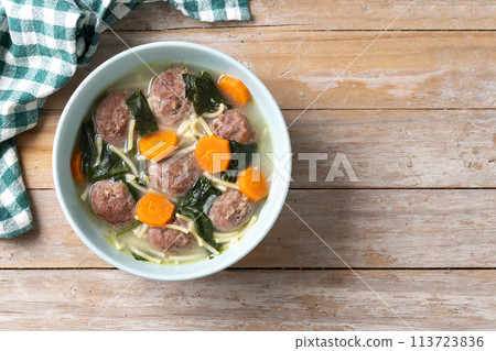 Italian Wedding Soup with meatballs and spinach on wooden table. Italian Wedding Soup with meatballs and spinach on wooden table. 113723836
