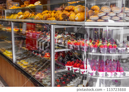 Assorted delicious fruit desserts, cakes and biscuits on shopwindow in caffee Assorted delicious fruit desserts, cakes and biscuits on shopwindow in caffee 113723888