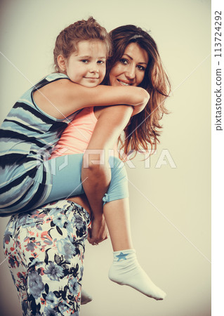 Mother parent giving kid piggyback ride. 113724292
