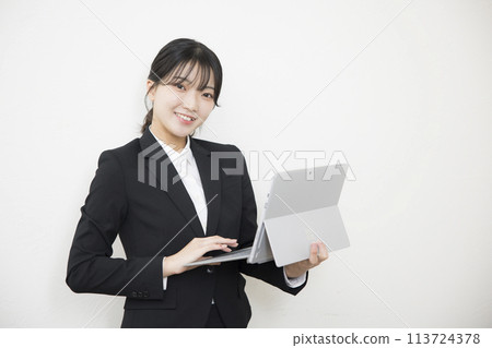 Smiling businesswoman holding a laptop 113724378