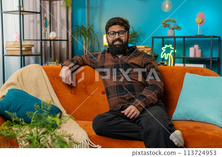 Portrait of happy Indian man looking at camera and smiling at home relaxing wearing eyeglasses 113724953