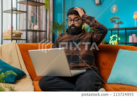 Amazed Indian man use laptop computer, receive good news message shocked by victory, celebrate win 113724955