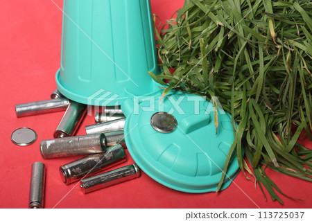 Creative display of recycled finger batteries in a small garbage bin, encouraging viewers to adopt sustainable habits for a cleaner planet. 113725037