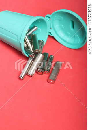 Used finger batteries in a miniature trash can. Pink background. Field for text. Used finger batteries in a miniature trash can. Pink background. Field for text. 113725038