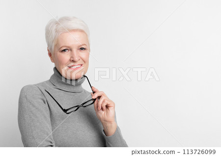 Portrait of a senior woman holding glasses 113726099