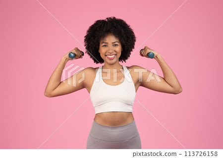 Smiling woman exercising with dumbbells 113726158