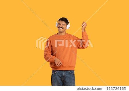 Man dancing with headphones on yellow background Man dancing with headphones on yellow background 113726165