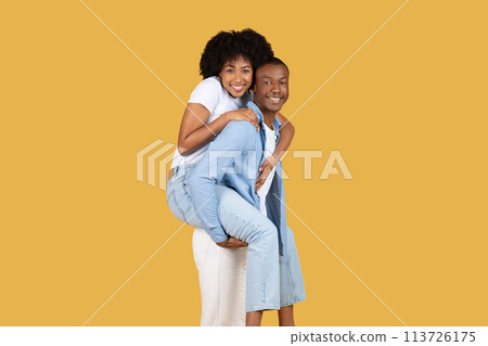 Playful African American couple enjoying a piggyback ride 113726175