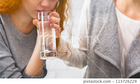 Psychotherapist comforting female patient, giving her glass of water to calm Psychotherapist comforting female patient, giving her glass of water to calm 113726229