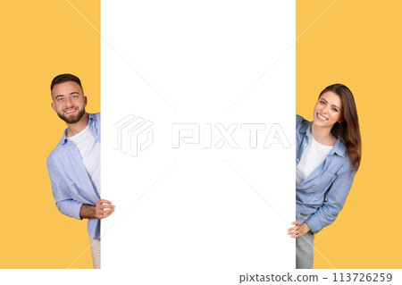 Couple peeking from behind a blank banner Couple peeking from behind a blank banner 113726259