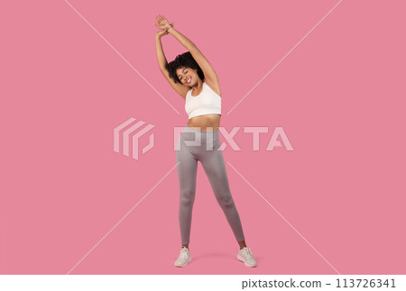 Sporty woman stretching on a pink background 113726341