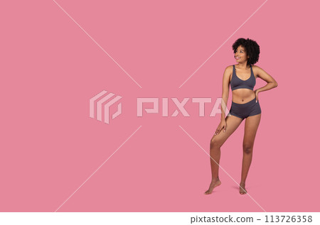 Standing African American lady in sportswear on pink background 113726358