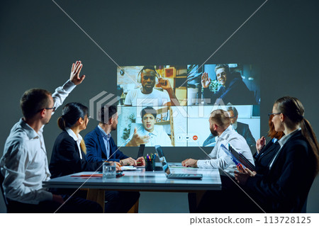 Office workers, colleagues gather around conference table, engaged in online meeting with remote colleagues. Project discussion Office workers, colleagues gather around conference table, engaged in online meeting with remote colleagues. Project discussion 113728125