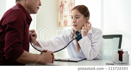 Female doctor asian cardiologist examining senior male cardiac patient listening checking heartbeat using stethoscope at checkup hospital visit. elderly healthcare cardiology concept 113728393