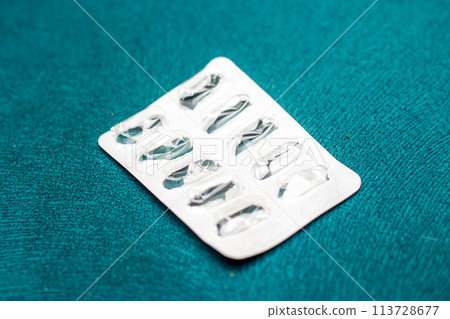 Pill blister pack on green surface in medical setting Pill blister pack on green surface in medical setting 113728677