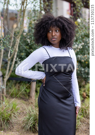 Confident Black Woman with Afro in Urban Garden Confident Black Woman with Afro in Urban Garden 113730135