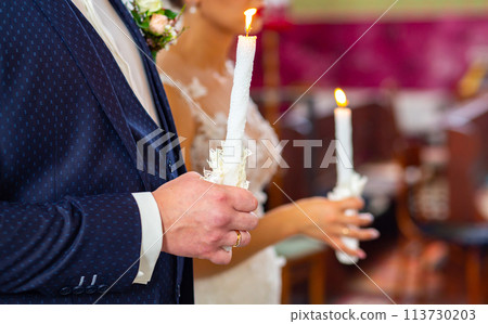 Bride and groom holding the candles. Close up. Bride and groom holding the candles. Close up. 113730203