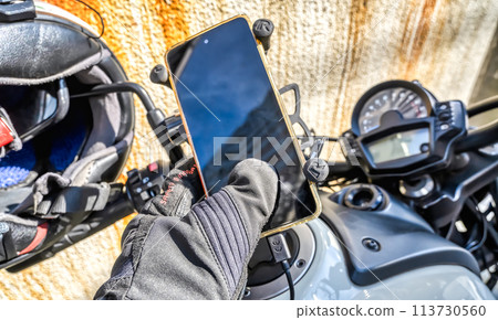 Motorcycle life: Rider operating smartphone with electric gloves Motorcycle life: Rider operating smartphone with electric gloves 113730560