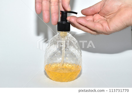 A bottle of liquid soap and a man's hands. 113731770