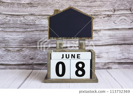 Chalkboard with June 08 date on white cube block on wooden table. 113732369